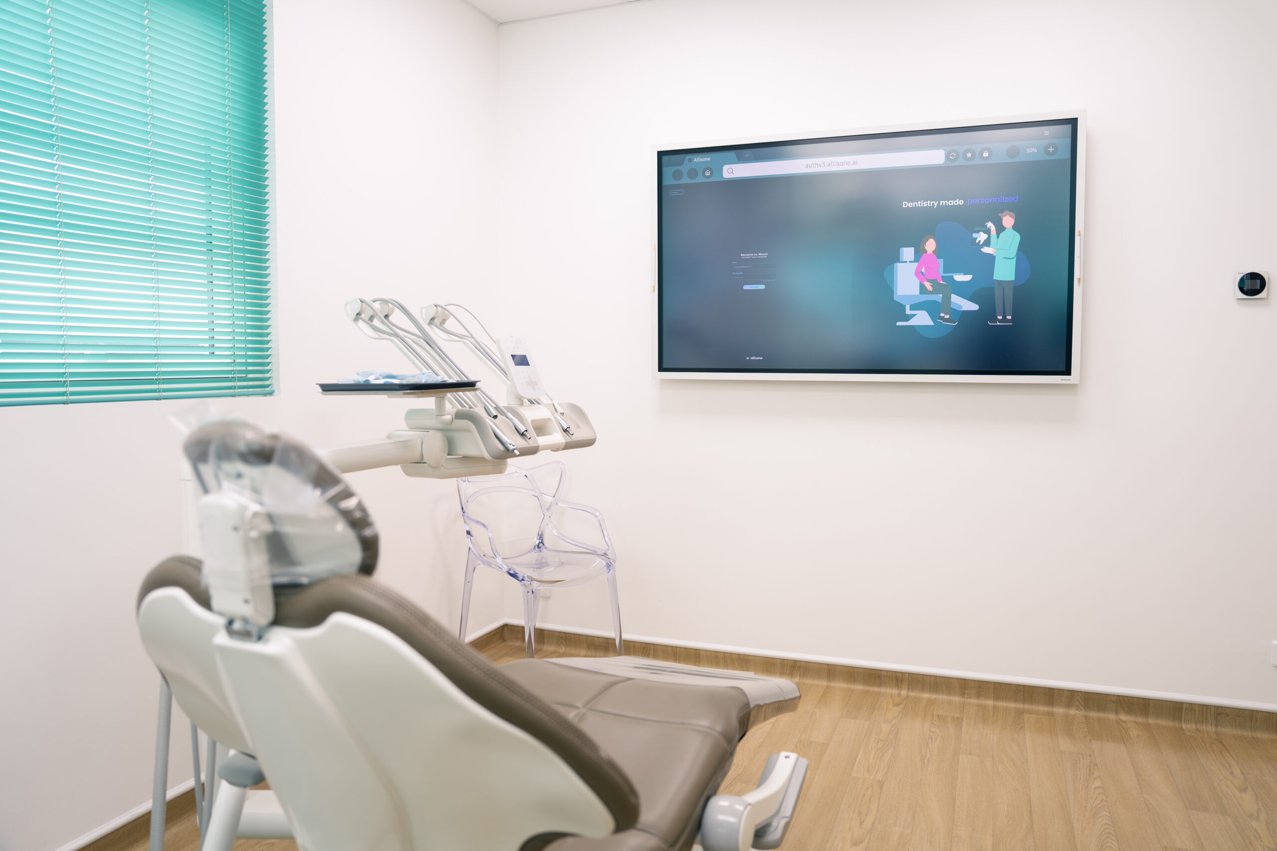 Salle de soins avec un fauteuil dentaire et un grand écran mural affichant une illustration